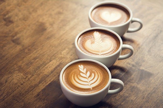 3 Kaffeetassen mit schönen Milchschaummustern auf einem Holztisch Quelle: Pixabay