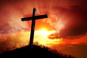 Bild Ein Kreuz auf einem Hügel vor einer untergehenden Sonne von Germán R auf Pixabay