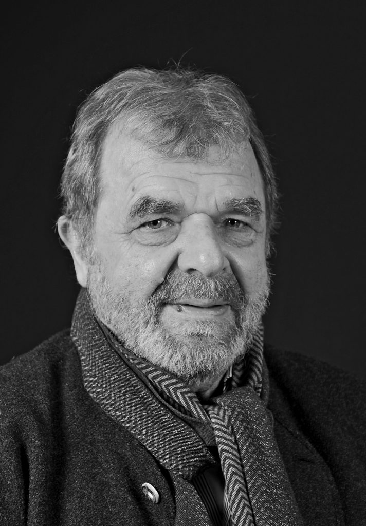 Ein schwarz-weiß Foto des ehemaligen Polizeibeamten und Autor des Buches "Todestransit", Erwin Müller. Herr Müller hat grau-melierte Haare und einen grau-melierten Vollbart. Er trägt einen Schal und eine Jacke mit Hornknöpfen.