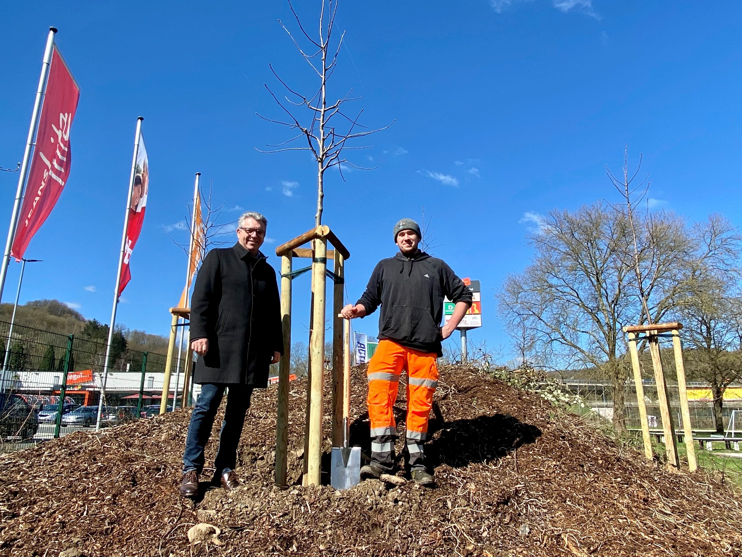 Bürgermeister Lotz und Gärtner-Auszubildender Corvin Bill zeigen neu gepflanzte Bäume