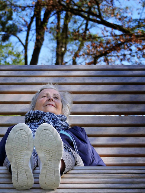 Eine ältere lächelnde Frau auf einer Bank.