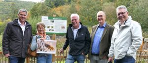 Fünf Personen vor der Bienenoase. Vier Männer und eine Frau, die ein Schild mit einer Biene darauf hält.