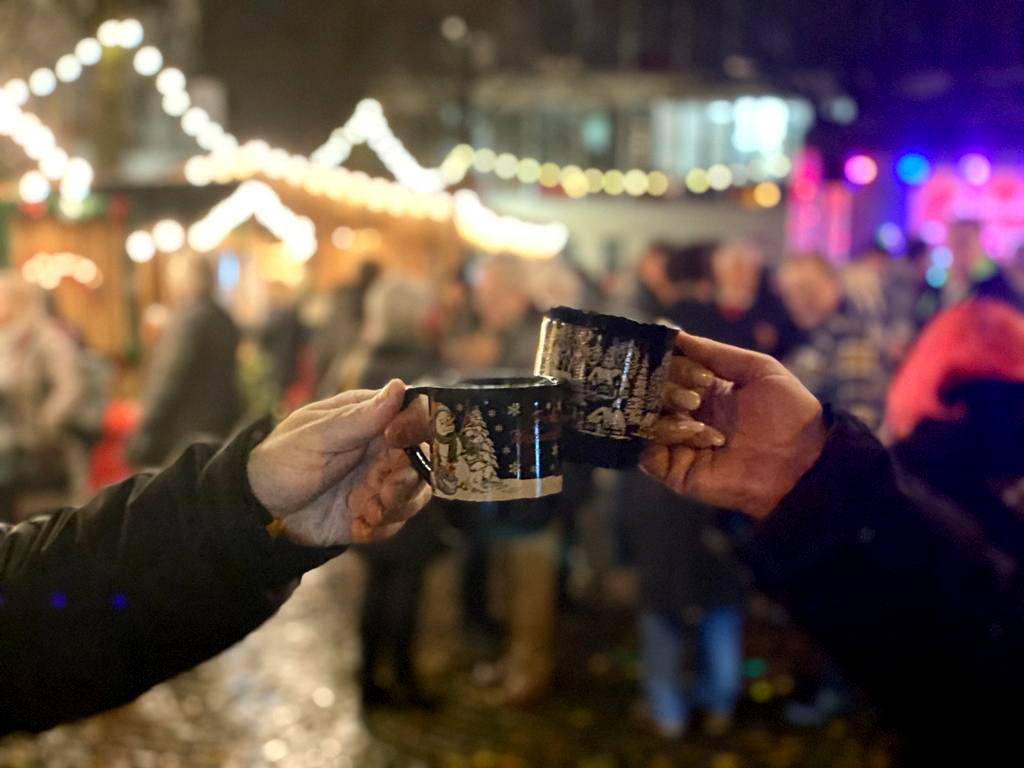 Zwei Hände die mit Glühweintassen anstoßen