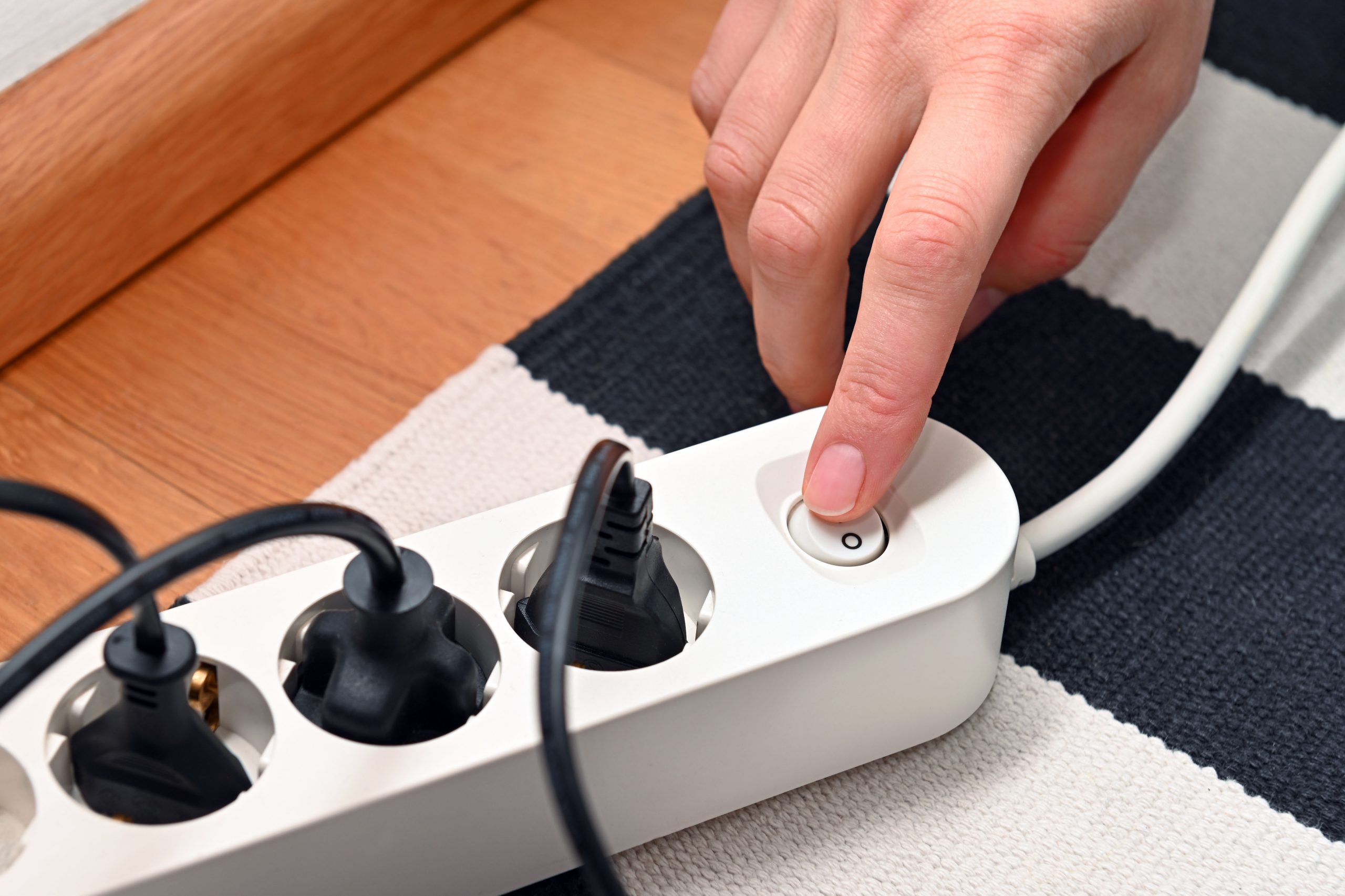 Eine Steckerleiste mit Schalter und eine Hand