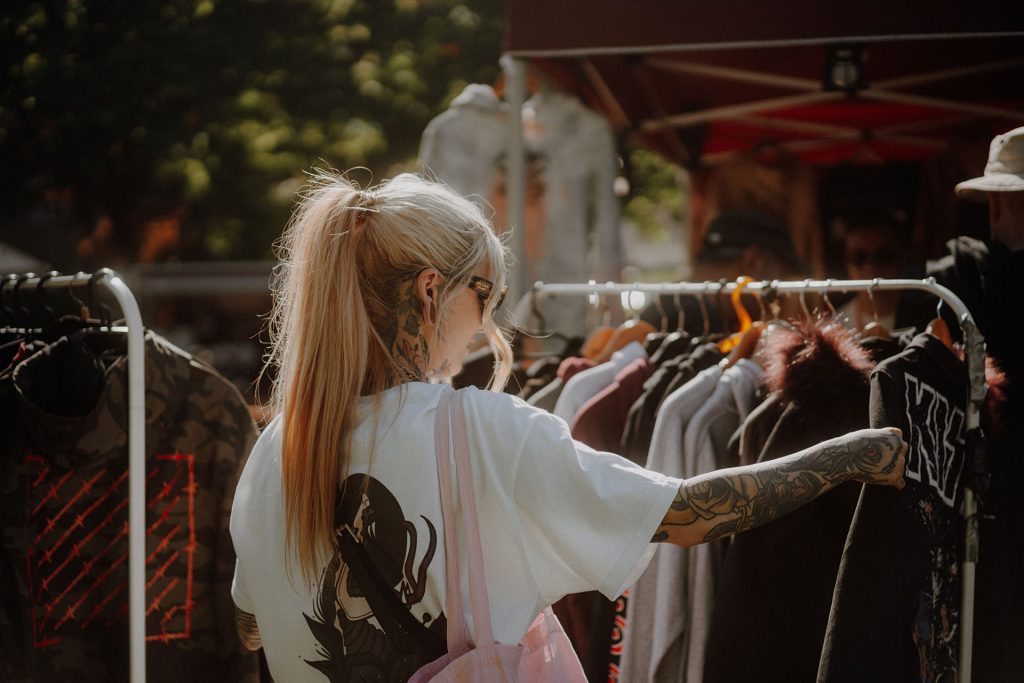 Tattoowierte Frau beim Durchsehen von Kleiderständern