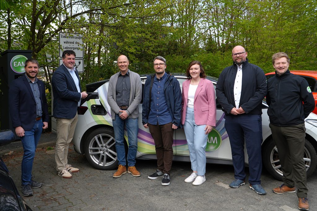 Menschen mit Auto an einer E-Ladesäule. Mit Klick aufs Bild geht´s zum ganzen Artikel