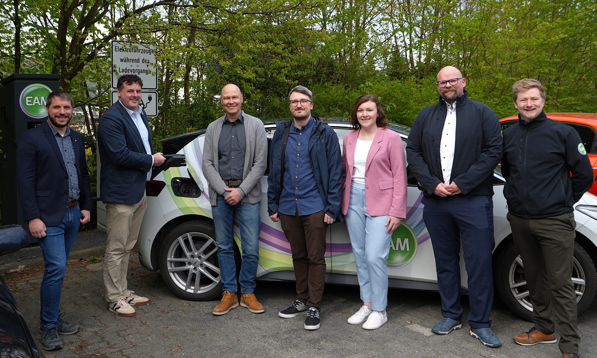 Menschen mit Auto an einer E-Ladesäule. Mit Klick aufs Bild geht´s zum ganzen Artikel