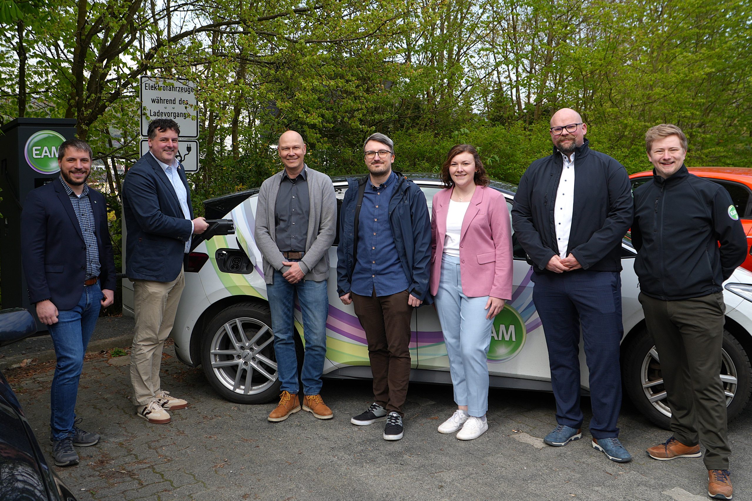 Menschen mit Auto an einer E-Ladesäule. Mit Klick aufs Bild geht´s zum ganzen Artikel