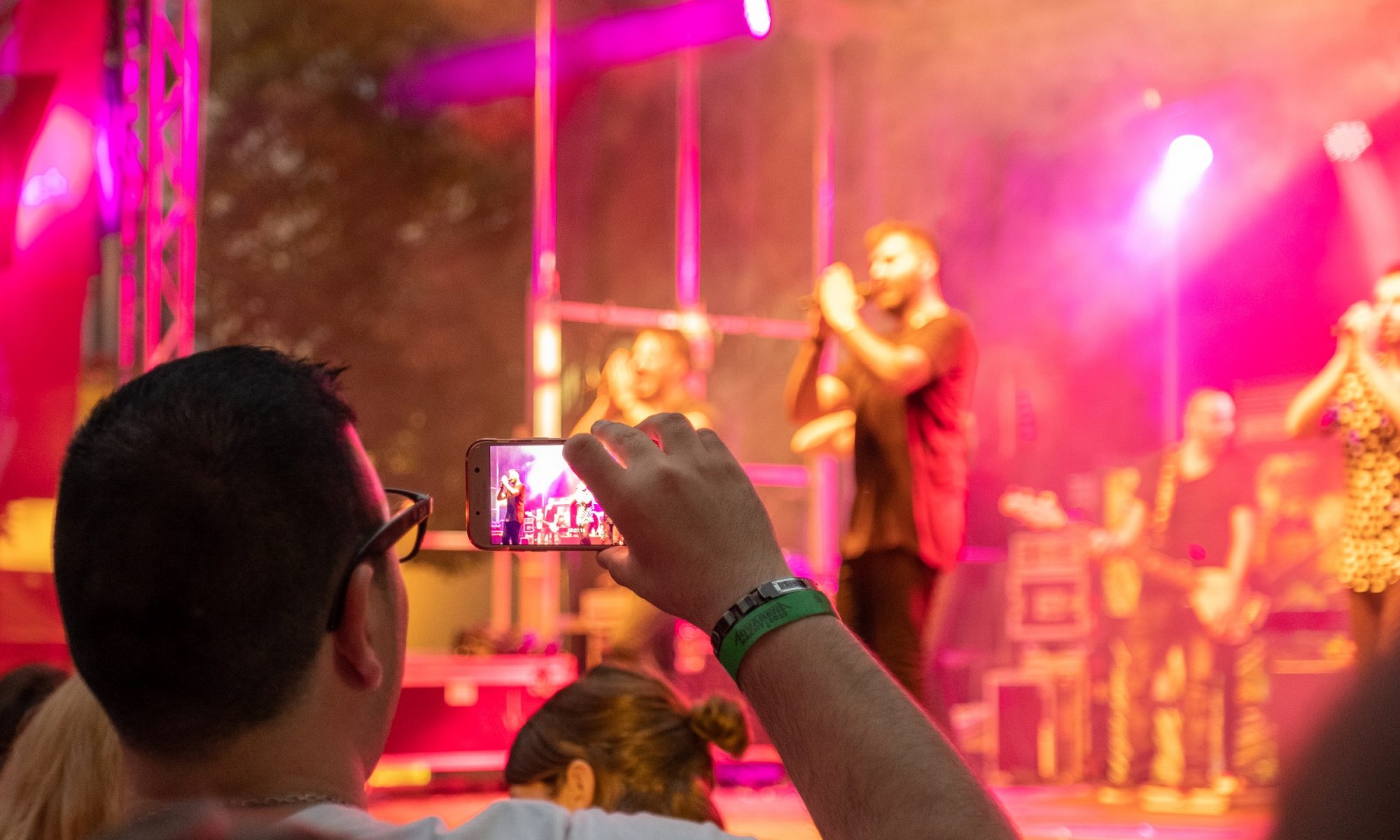 Ein Konzertbesucher filmt durch sein Handy die Band auf der Bühne