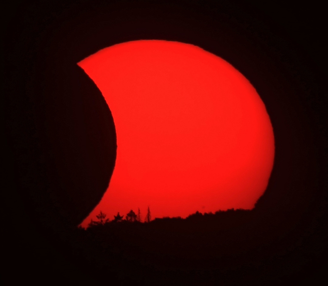 Sonne berührt den Horizont während der partiellen Sonnenfinsternis.