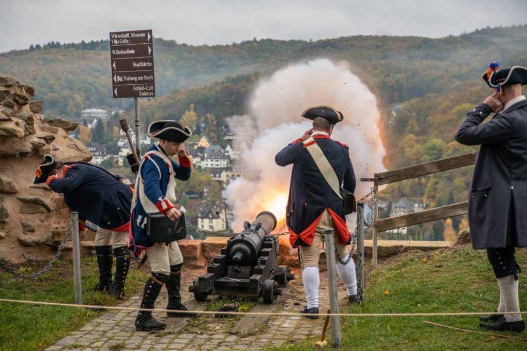 Historisch gekleidete Personen feuern eine Kanone ab